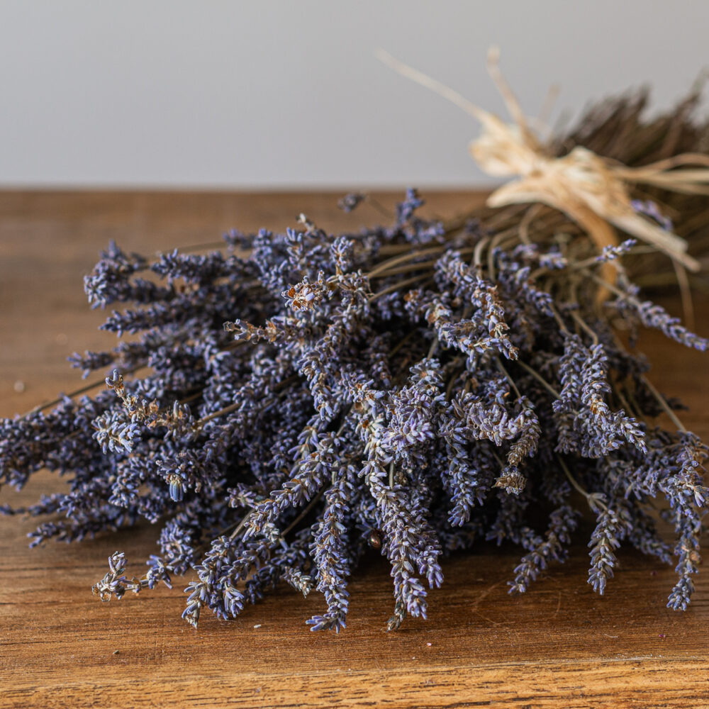 The "Dried Lavender" is elegantly tied with twine and rests beautifully on a wooden surface.