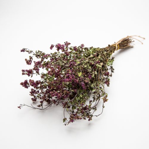 A bundle of dried purple and green herbs tied together with string, placed on a plain white background.